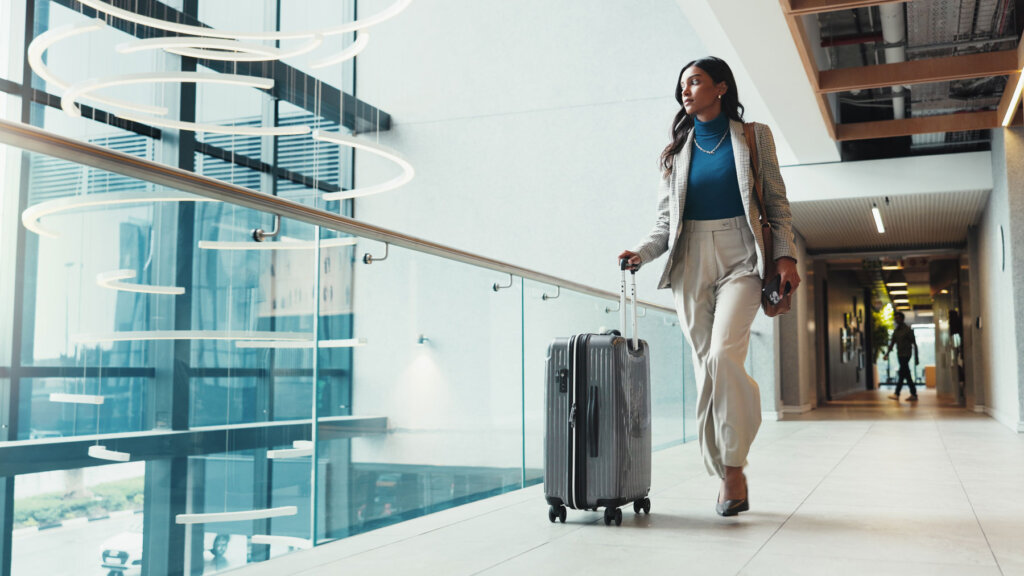 A travel advisor who has elevated her career by becoming a luxury travel advisor with Andavo Travel walking through an airport with her suitcase