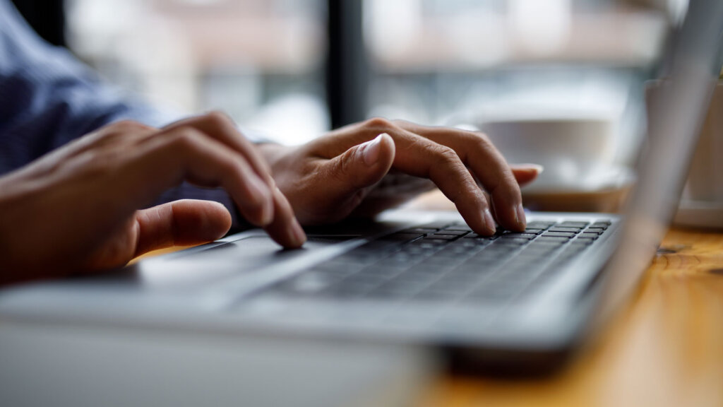 A travel agent researching the difference between a travel agent and a luxury travel advisor on a laptop